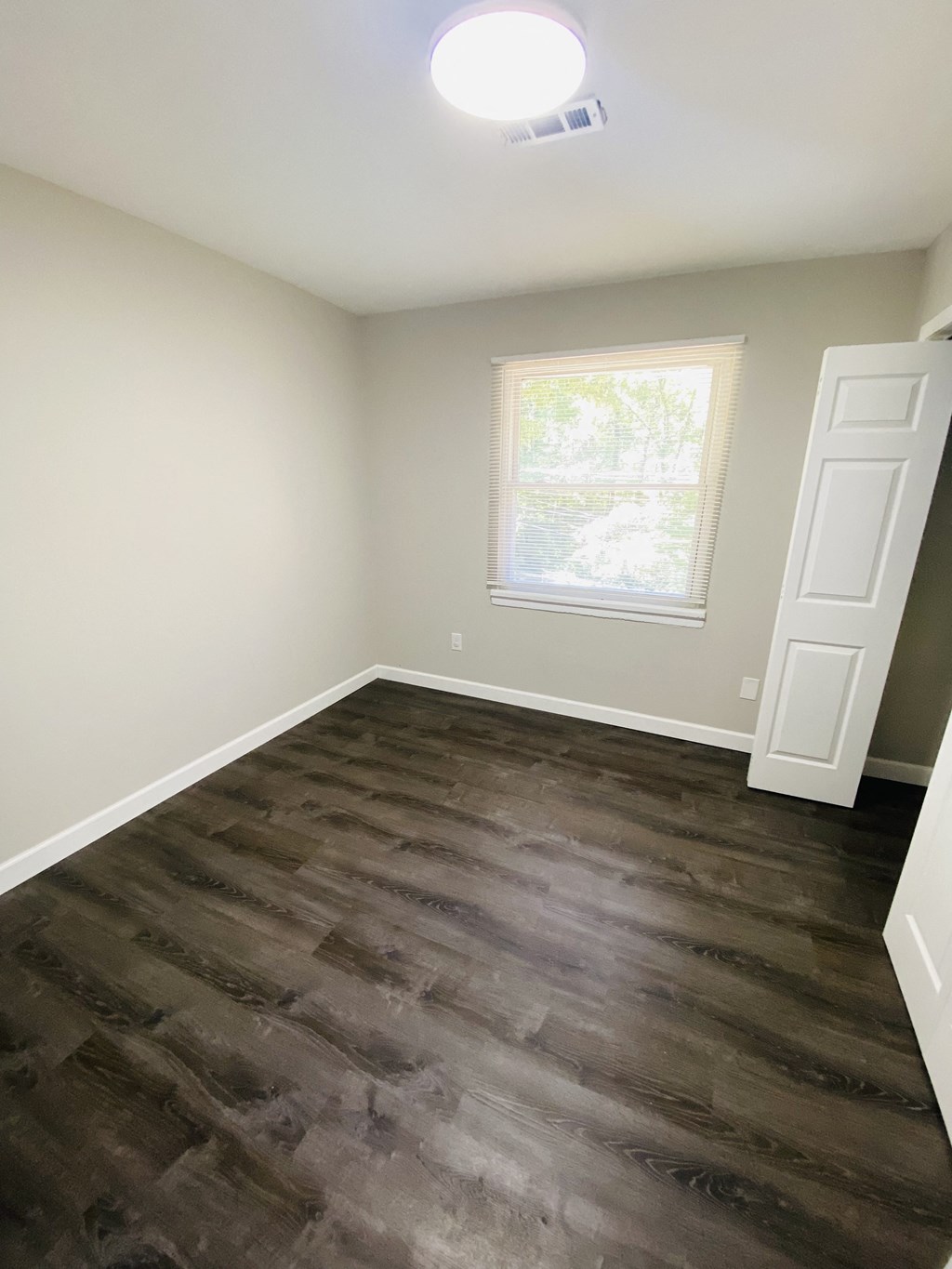 an empty room with wooden floors and a window