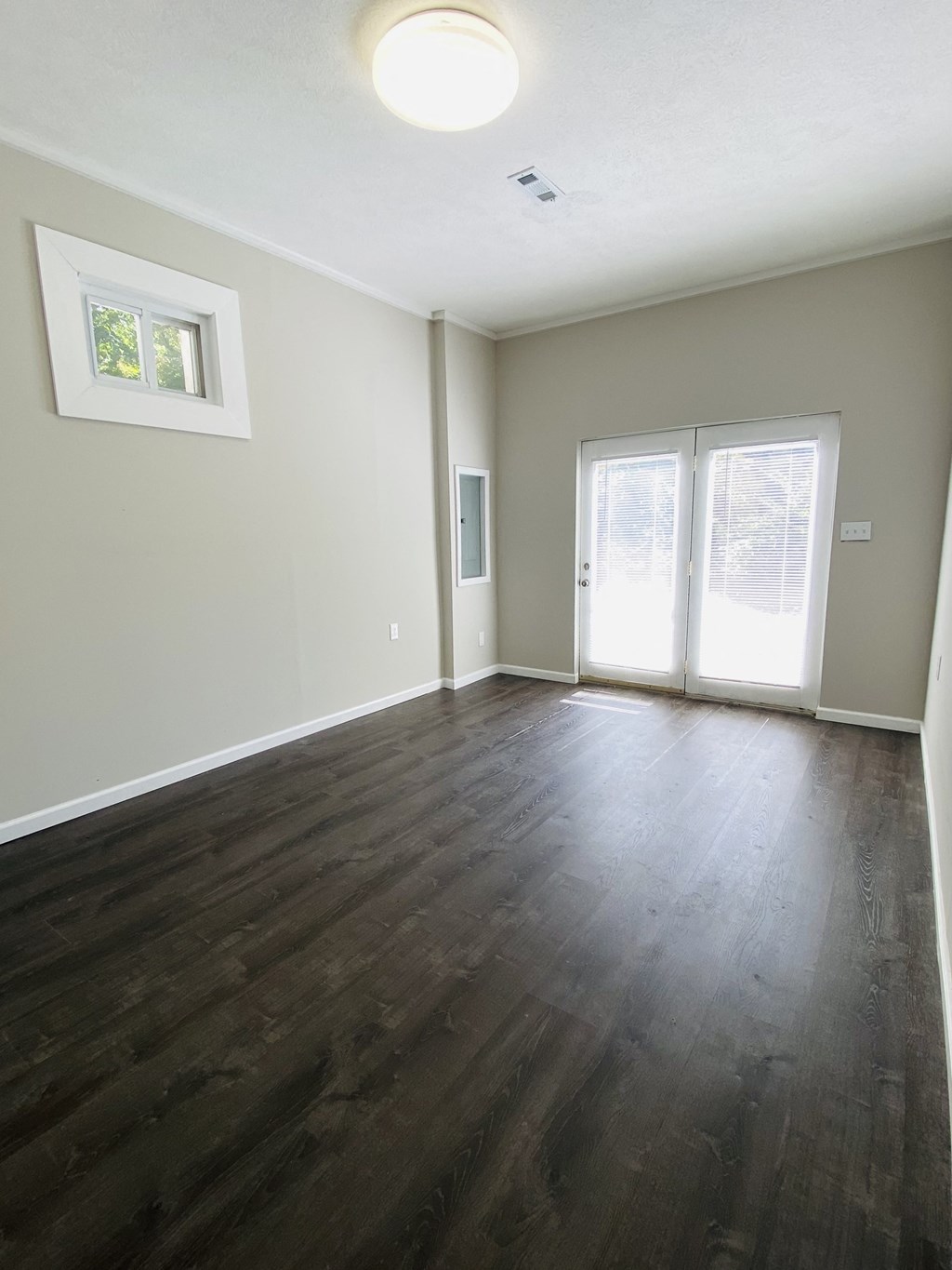 an empty living room with wood floors and a door to a balcony