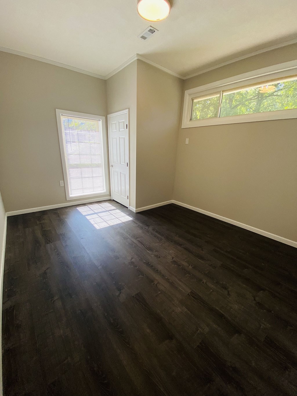 an empty living room with hard wood floors and a window