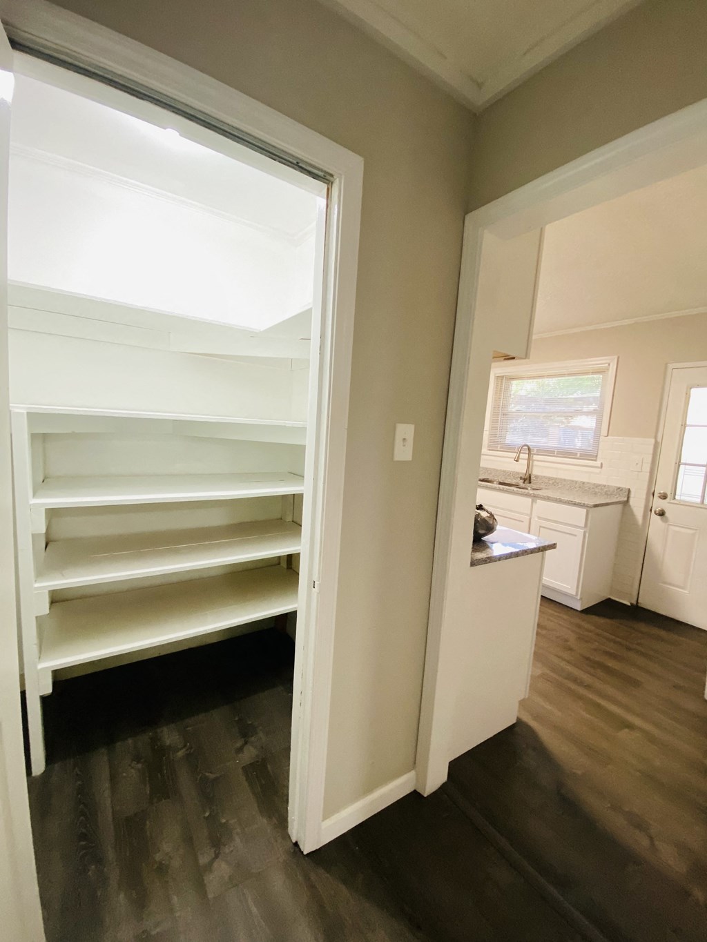 a hidden pantry with empty shelves in a room with a kitchen