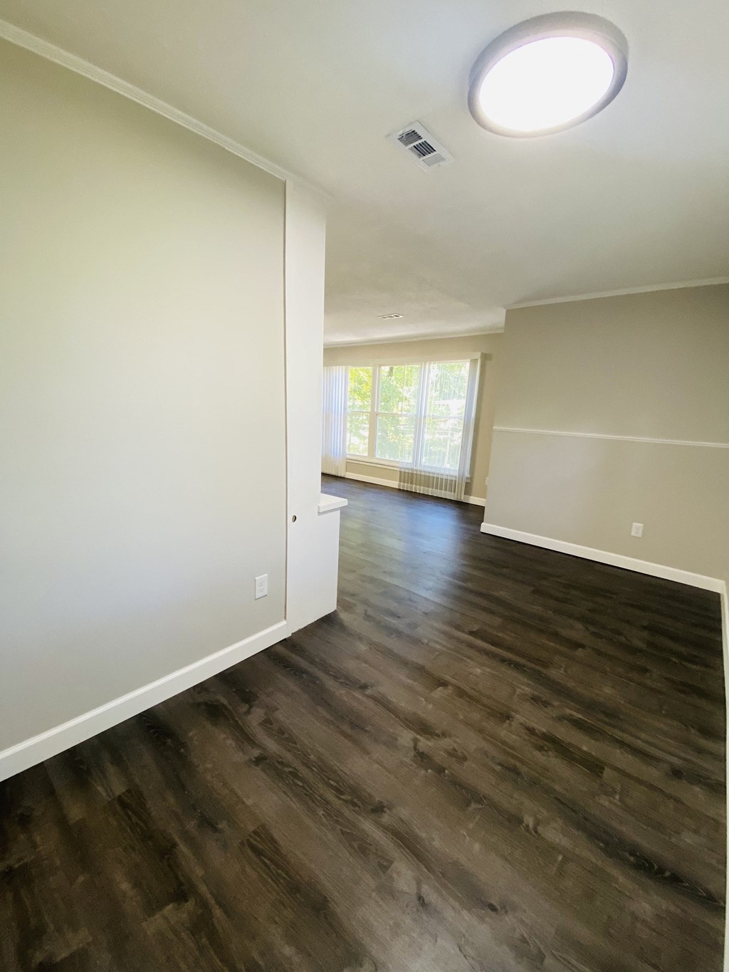 an empty living room with wooden floors and white walls