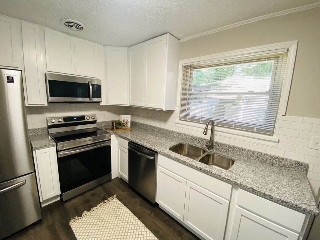an updated kitchen with granite counter tops and stainless steel appliances