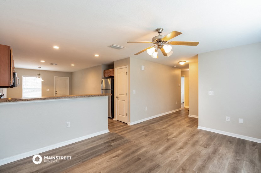 a living room with a kitchen and a ceiling fan