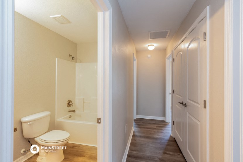 a bathroom with a toilet and a shower and a hallway with a white door