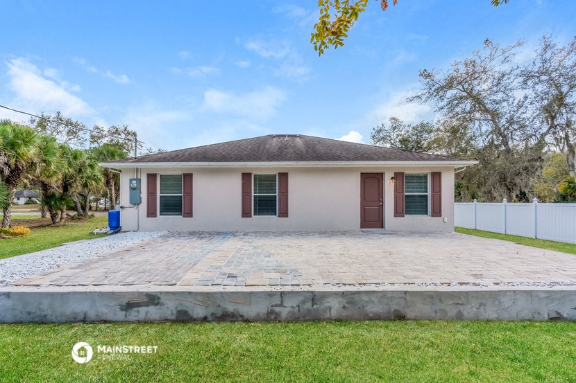 a small white house with a driveway and a grassy yard