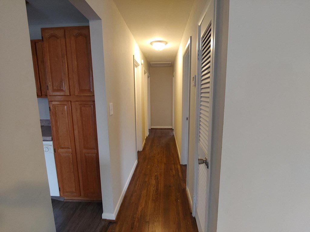 a hallway with wood floors and white walls and a closet