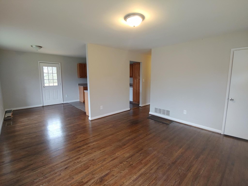 an empty living room with wood floors and white walls