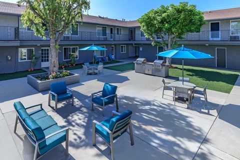an outdoor patio with blue chairs and umbrellas and a building in the background