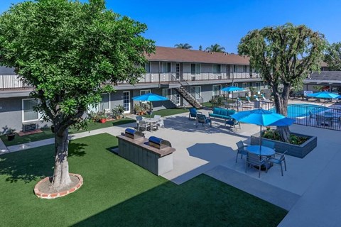 a patio with tables and umbrellas and a swimming pool