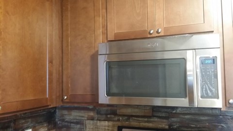 a kitchen with a stainless steel microwave and wooden cabinets