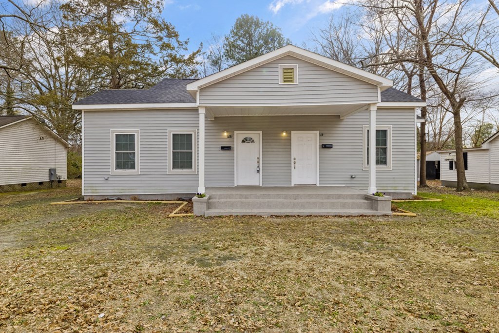 the front of a white house with a porch and a lawn