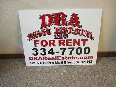 A sign for DRA Real Estate LLC is displayed on a carpeted floor.