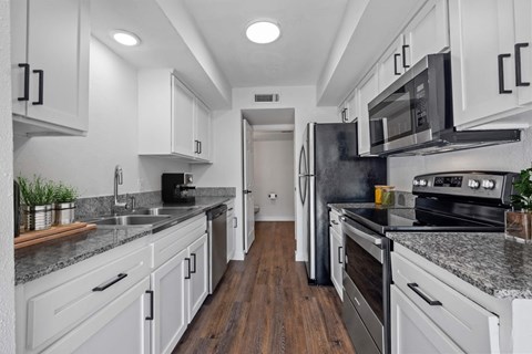 a kitchen with white cabinets and black appliances