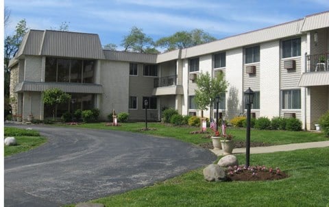 an exterior view of an apartment building with a curved road in front