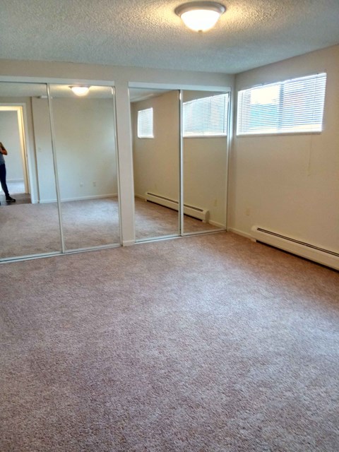 an empty living room with mirrored closet doors