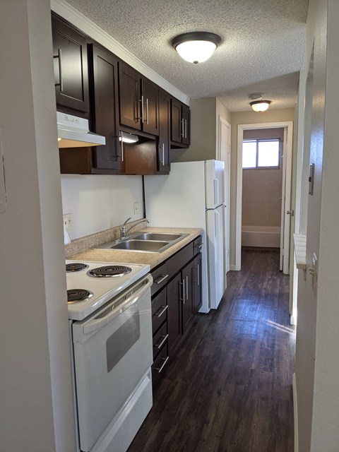 a kitchen with white appliances and wooden floors
