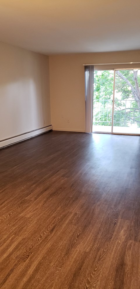 an empty living room with wood floors and a window