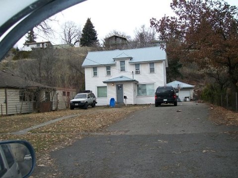 A white house with a black car parked in front.