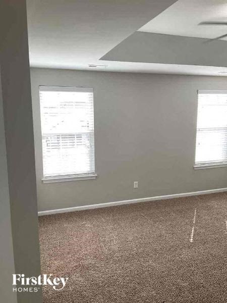 an empty room with two windows and a carpet