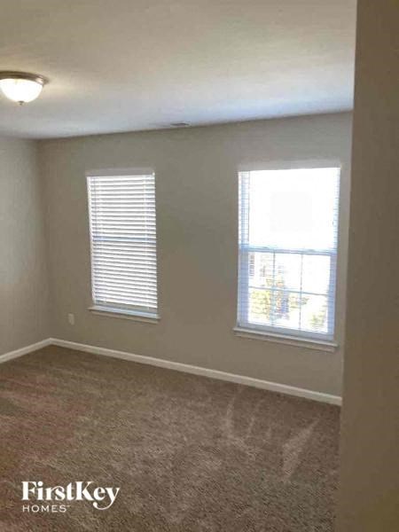 an empty bedroom with two windows and a carpeted floor