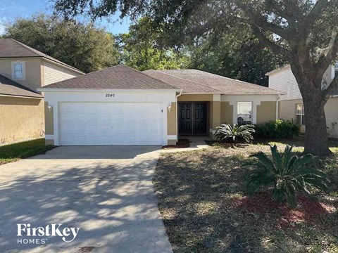 A house with a garage and a tree in front of it.