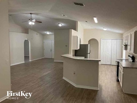A spacious kitchen and living room with wood flooring and white walls.