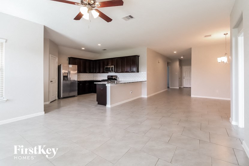 A spacious kitchen and living room with a fan on the ceiling.