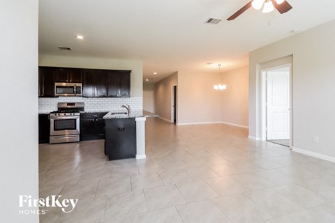 A kitchen with a black counter top and a white tile floor.