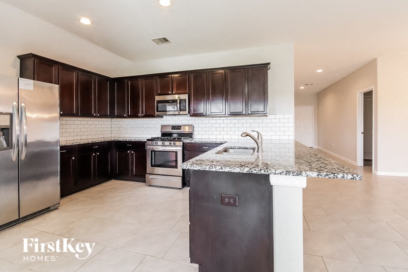 A kitchen with a refrigerator, microwave, oven, and sink.