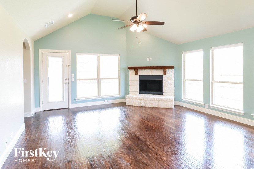 an empty living room with a fireplace and a ceiling fan