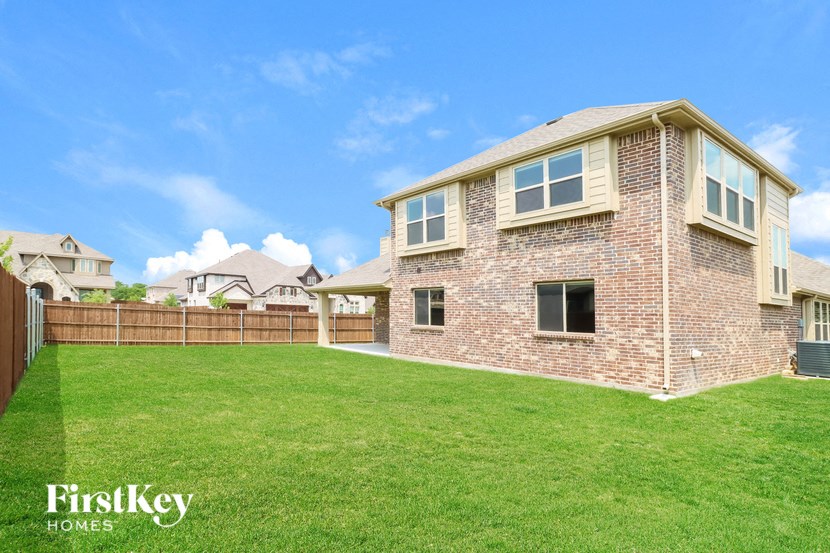 a backyard with a brick house and a green lawn