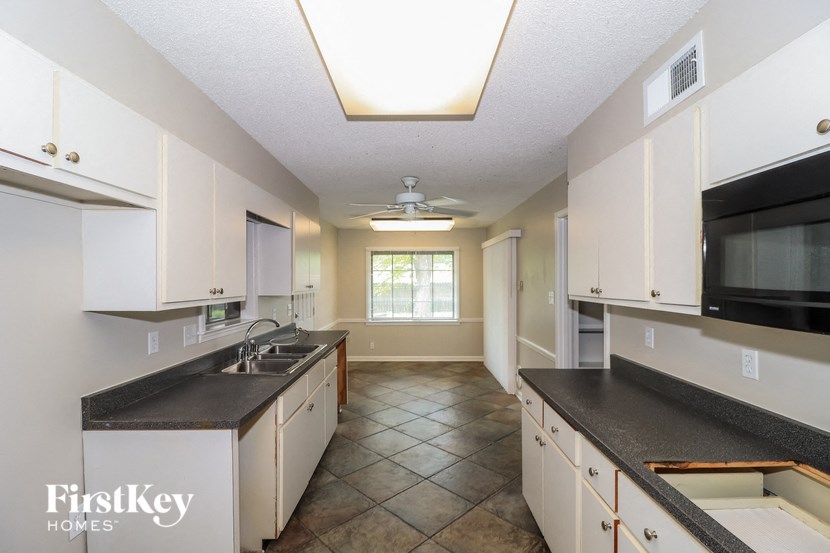 A kitchen with white cabinets and a black counter top.