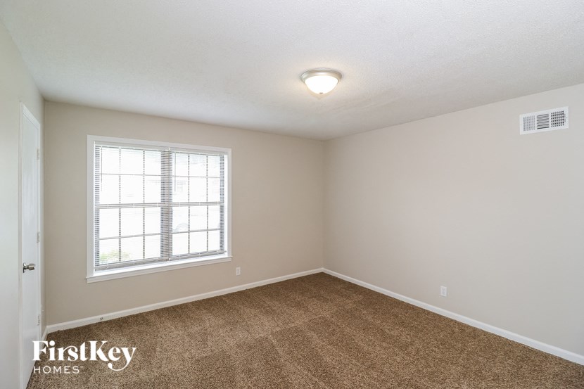 A room with a window and carpeted floor.