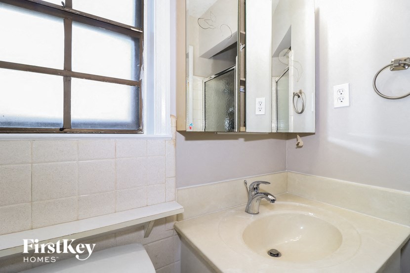 A bathroom with a sink, mirror, and window.