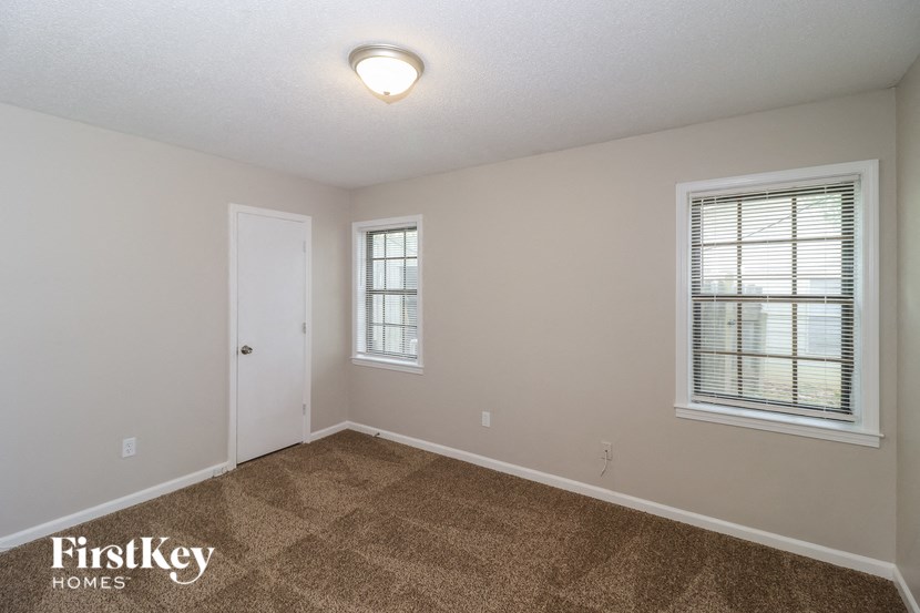 A room with a carpeted floor and a window with blinds.