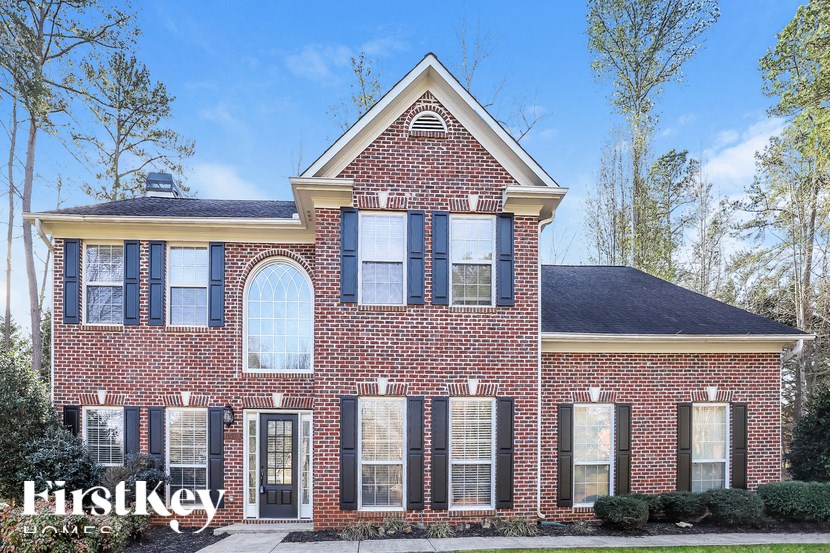 a red brick house with black shutters and a blue sky