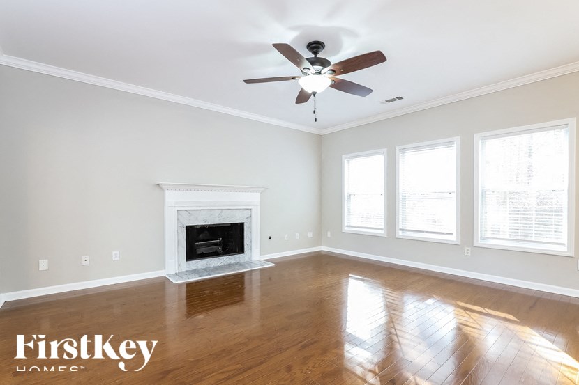 an empty living room with a ceiling fan and a fireplace