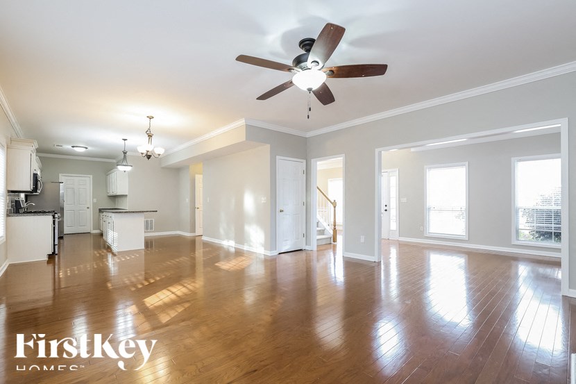 an empty living room and kitchen with a ceiling fan