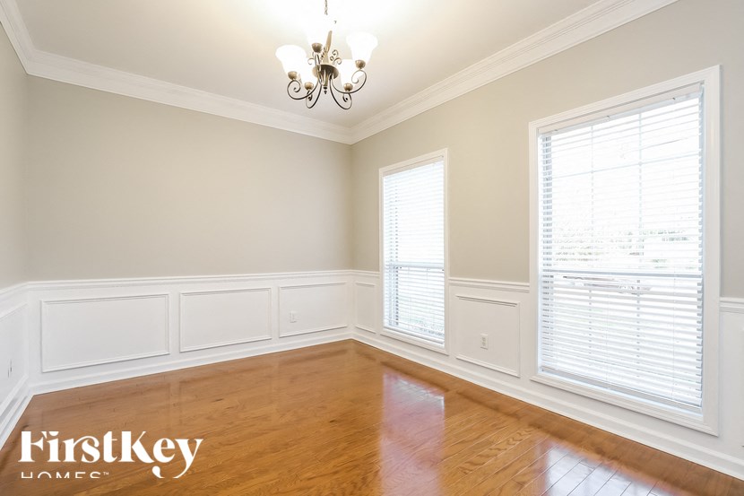 an empty living room with wood floors and a chandelier