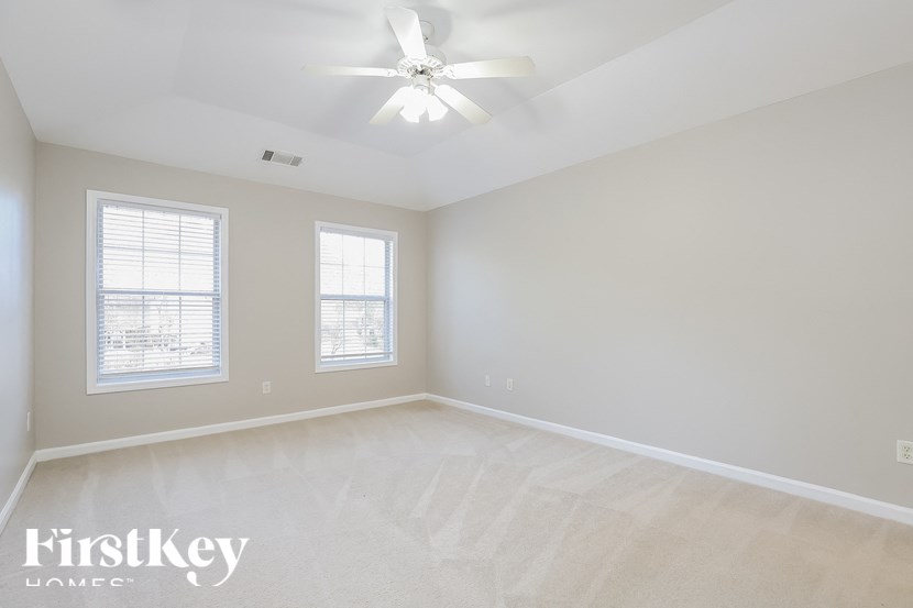 an empty bedroom with a ceiling fan and two windows