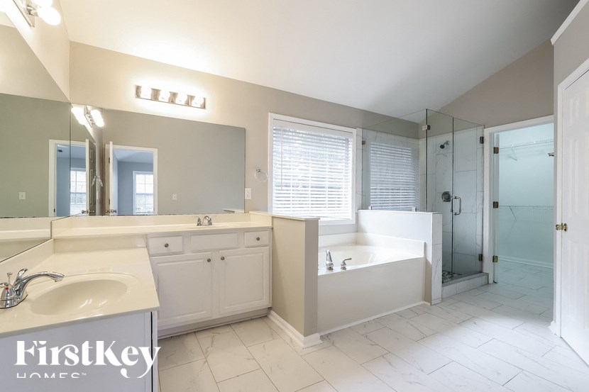 a large bathroom with a tub and a sink and a mirror