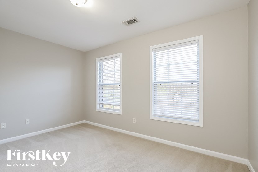 a bedroom with two windows and a carpeted floor