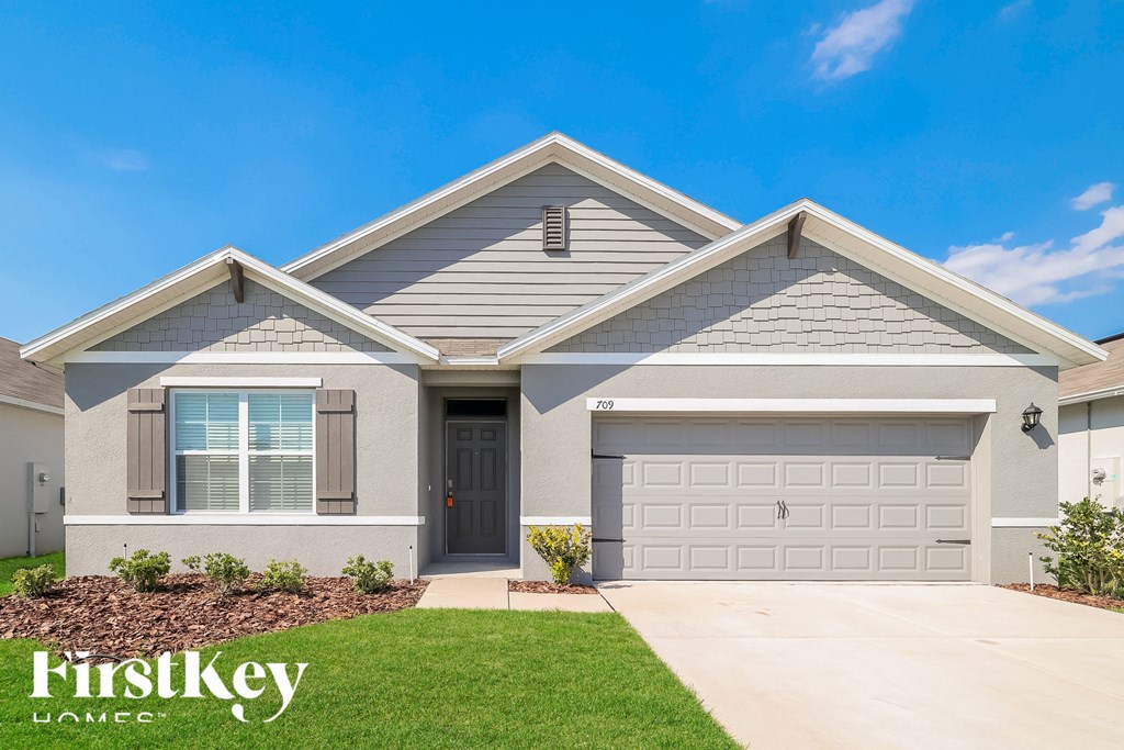 a beige house with a garage door and a lawn