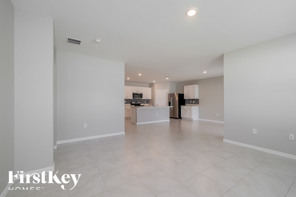 a large empty living room with a kitchen in the background