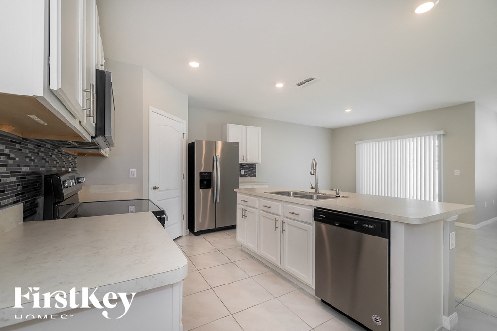 a white kitchen with stainless steel appliances and white counter tops