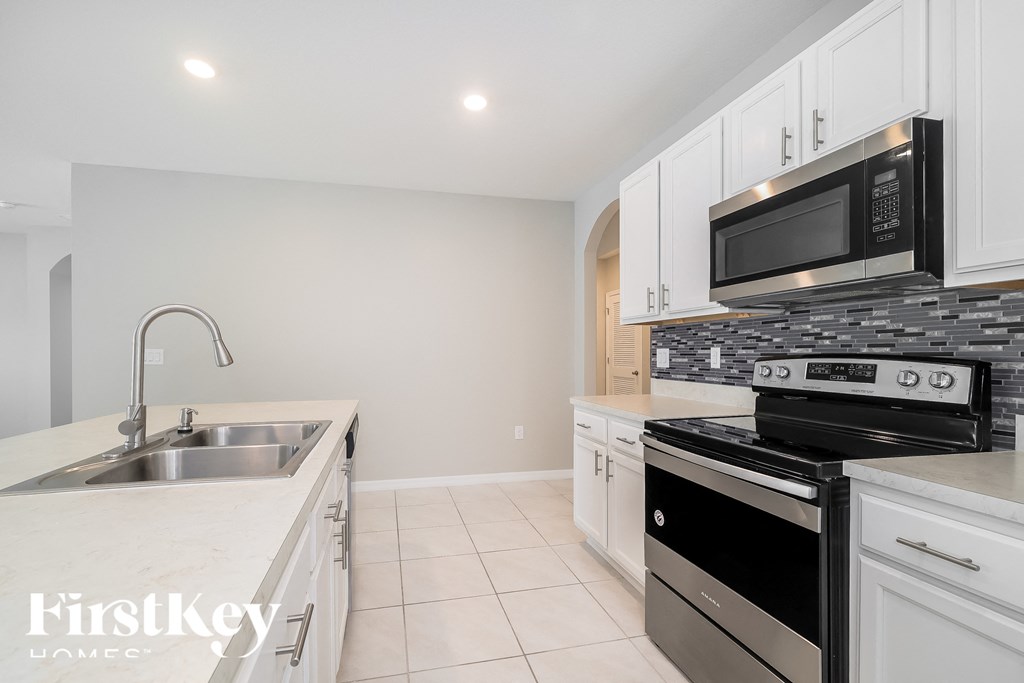 a kitchen with white cabinets and black appliances and a sink