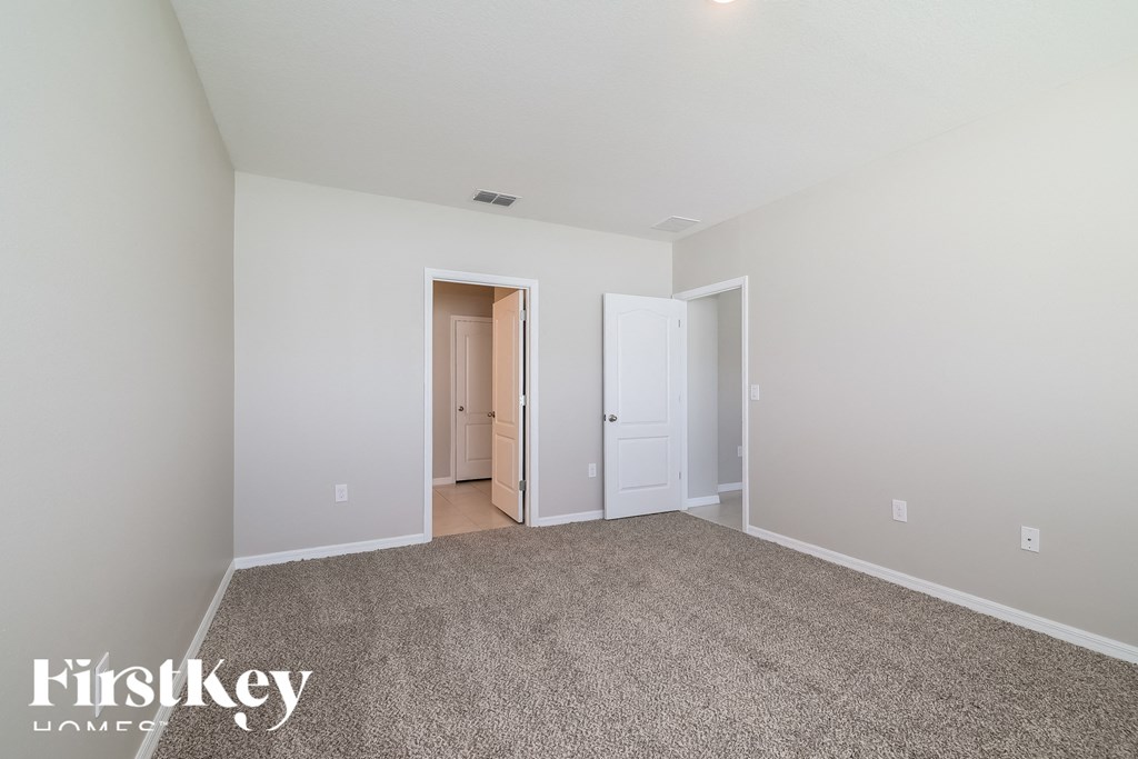 a master bedroom with carpeting and a door to a hallway