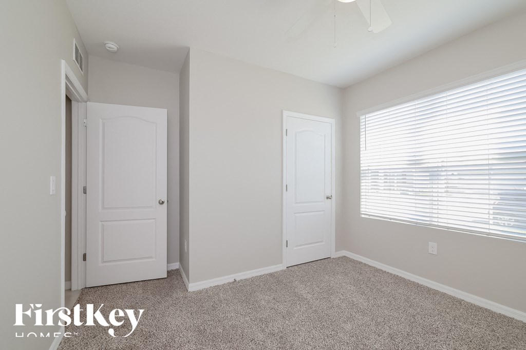 a bedroom with two doors and a window and a carpeted floor