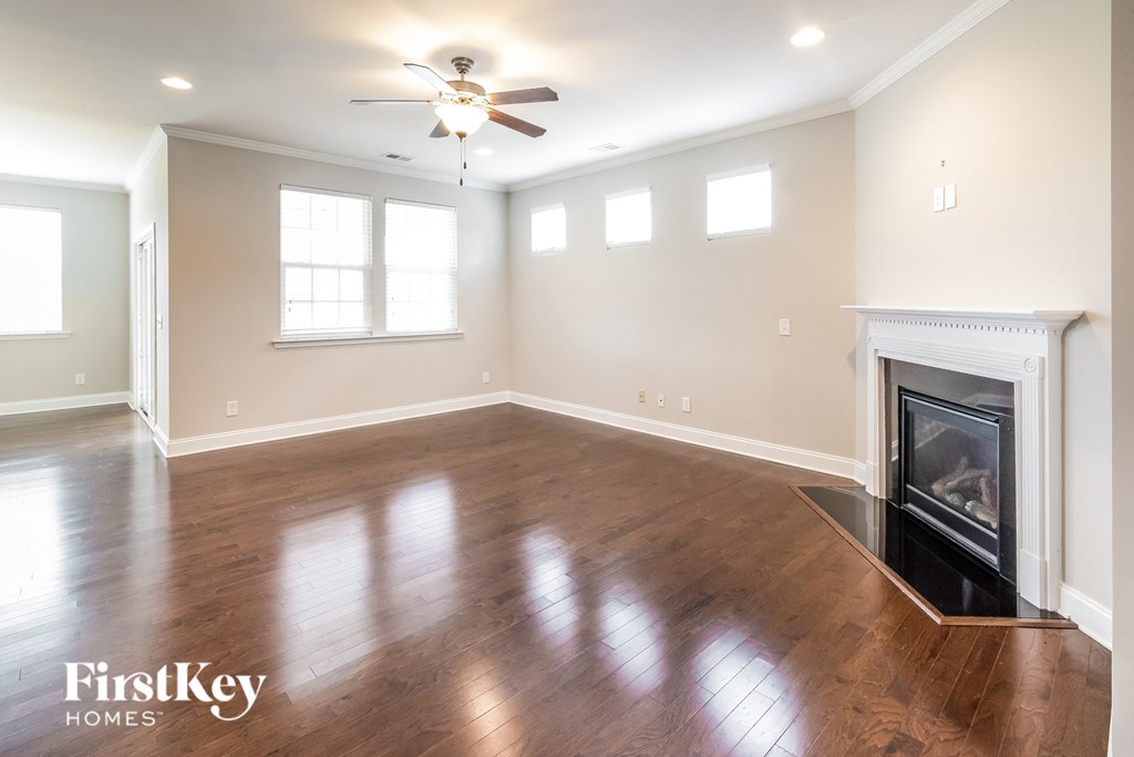 an empty living room with a fireplace and a ceiling fan