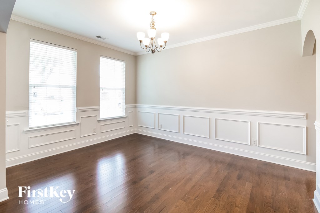 a dining room with white walls and wood floors and a chandelier